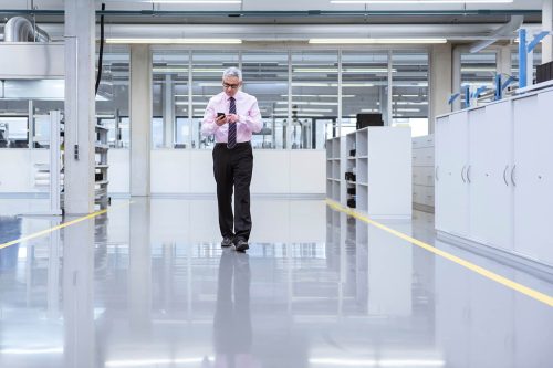 Manager on shop floor of a factory using smart phone